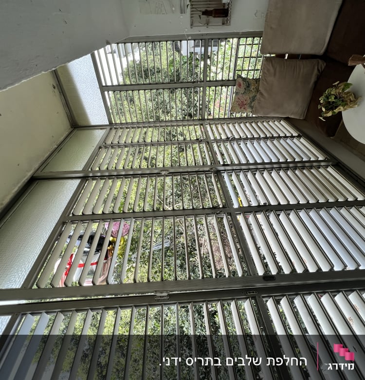 תריסים אופקיים מתכתיים על חלון זכוכית